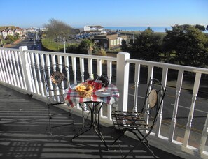 A balcony with a table set for two, a chair, and a decorative item. - Seabreeze Apartment – Stunning Sea Views & Perfect Location (Eastbourne)