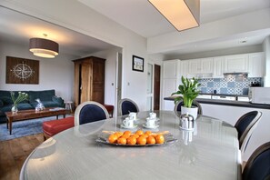 A modern kitchen with white cabinets, a tiled backsplash, and a dining area with a round table set for four.