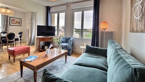 Ein Wohnzimmer mit einer Couch, einem Couchtisch, einem Fernseher und Blick auf die Stadt.