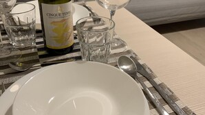 A dining setup with a wine bottle, plates, glasses, and cutlery on a table.
