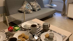 A neatly arranged dining area with a striped tablecloth, a coffee maker, and a variety of breakfast items.