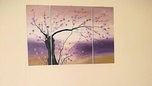 A bedroom with a bed, a nightstand, and a wall-mounted painting of a tree. - Apartment in the center of Sliema (Tas-Sliema)