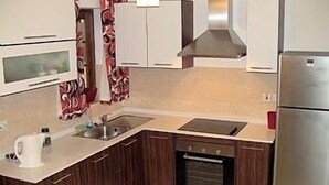 A modern kitchen with wooden cabinets, a built-in oven, a stainless steel refrigerator, and a microwave. - Apartment in the center of Sliema (Tas-Sliema)