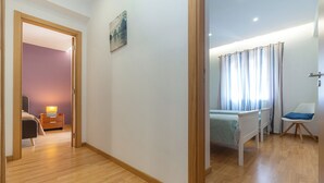 Un dormitorio con cama, una silla, una mesita de noche y una ventana con cortinas.