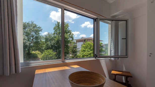 Una habitación con un ventanal grande, una mesa de madera y un cuenco.