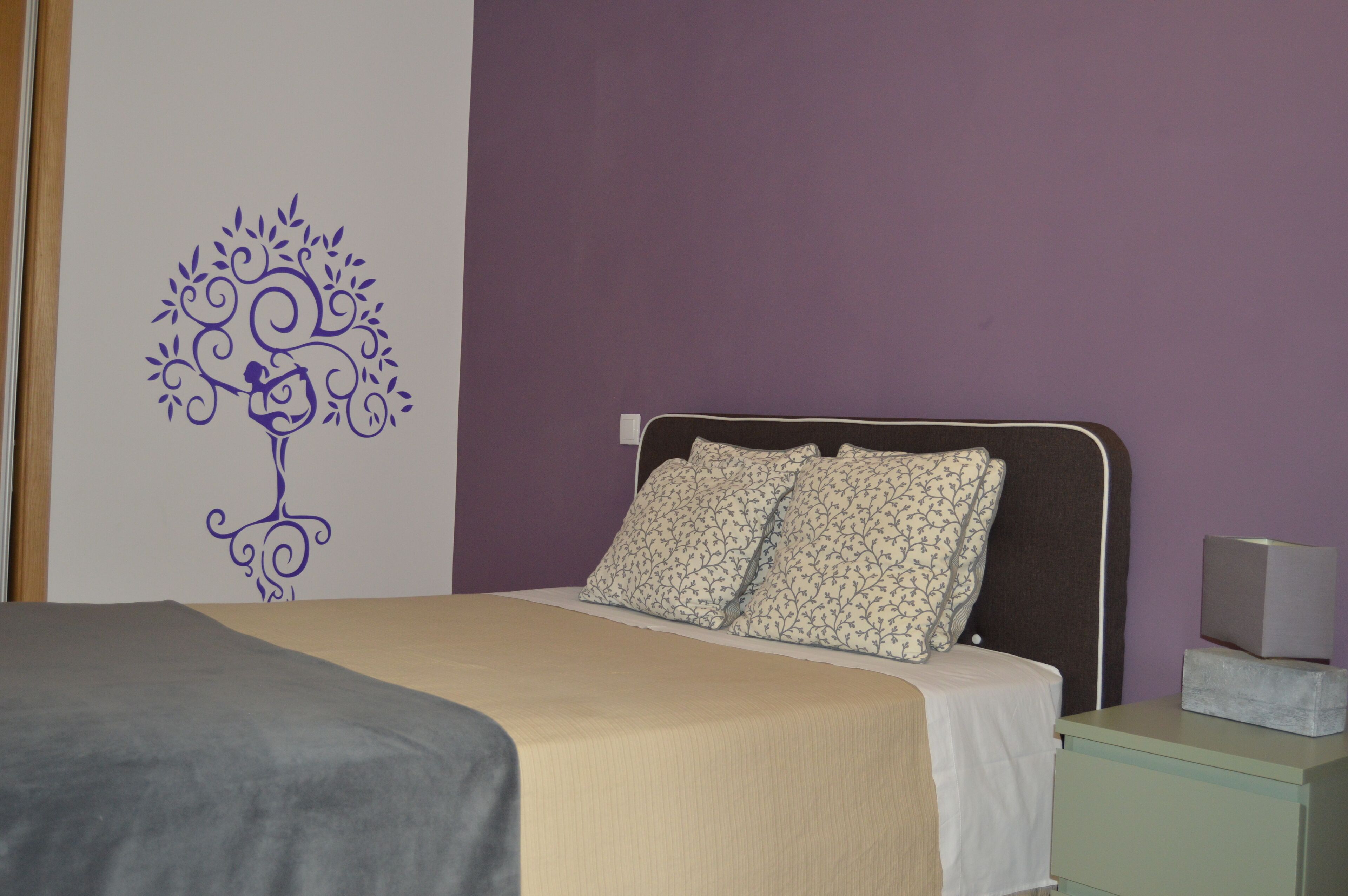 Een slaapkamer met een bed, een nachtkastje en een decoratie aan de muur.