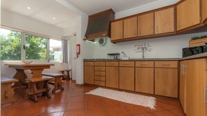 Una cocina con armarios de madera, piso de baldosas y una ventana que deja entrar luz natural.