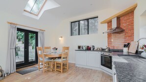 Une cuisine moderne dotée d’une lucarne, un coin repas avec une table et des chaises, et un mur décoratif en briques.