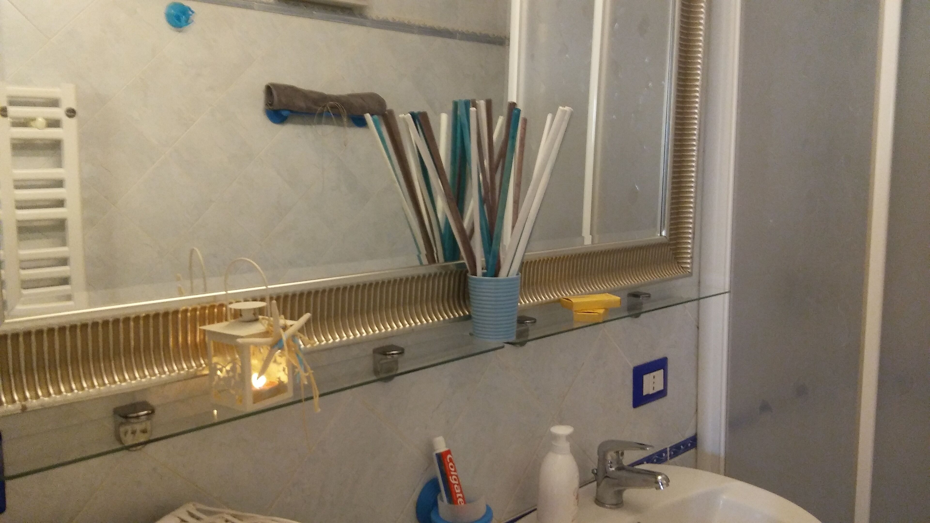 Une salle de bain avec un miroir, un porte-brosse à dents et un lavabo.