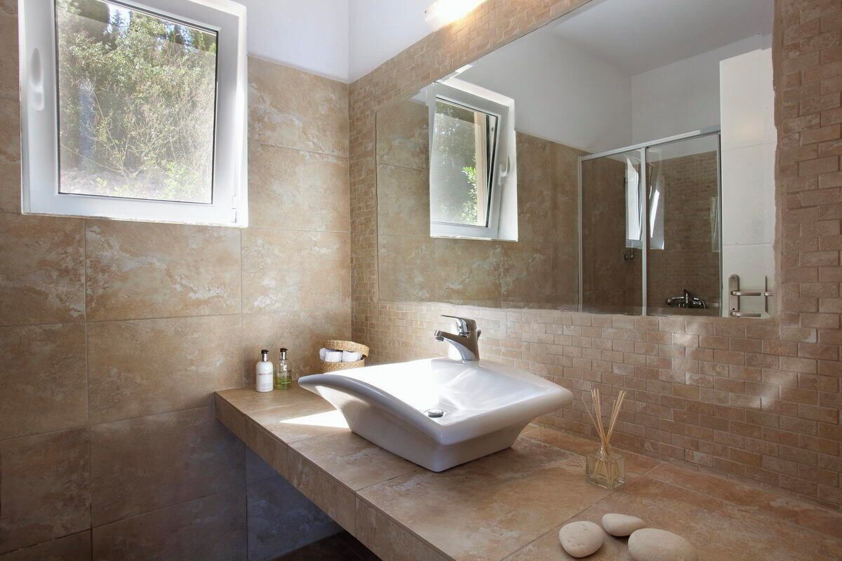 Ein modernes Badezimmer mit einem großen Waschbecken, einem Spiegel und einem Fenster.