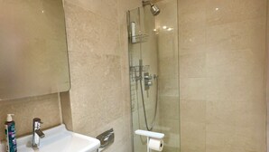 Uma casa de banho moderna com chuveiro em cabine de vidro, lavatório branco e sanita.