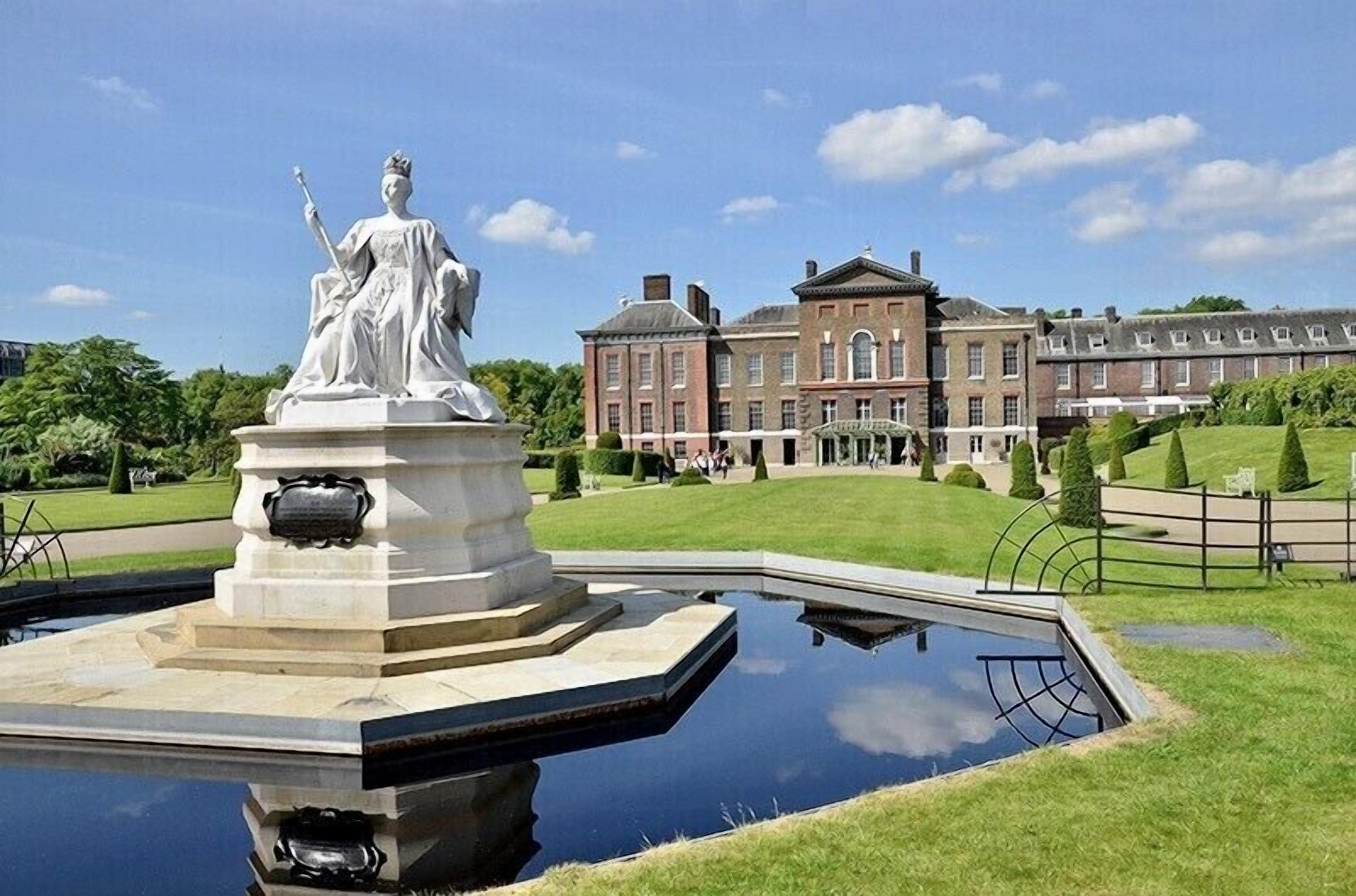 En statue i en springvand med en stor bygning i baggrunden.