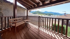 A wooden deck with a bench, a stone wall, and a view of mountains.