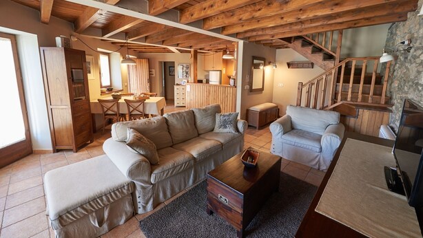 A spacious living area with a wooden ceiling, a sofa, a coffee table, and a television.