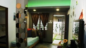 A compact living space with a bed, a small table, and a TV. - The Retreat Homestay (Tanjung Malim)