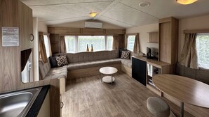 A spacious RV interior with a kitchen area, seating, and a small table. - Chalet Lynn on the beach and sea (Oosterschelde) (Kamperland)