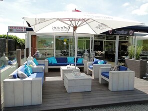 An outdoor seating area with white furniture and a large umbrella.