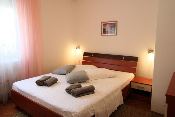A neatly made bed with rolled towels, a wooden headboard, and bedside lamps. - Spacious 4-Bedroom Oasis for 8, No Pets, 3 Parking Spaces (Ližnjan)