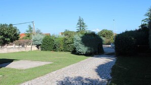 A paved pathway in a landscaped area with grass and trees.