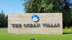 Ein Schild für The Ocean Villas mit einem Logo, das ein Segelboot und einen Mond zeigt.