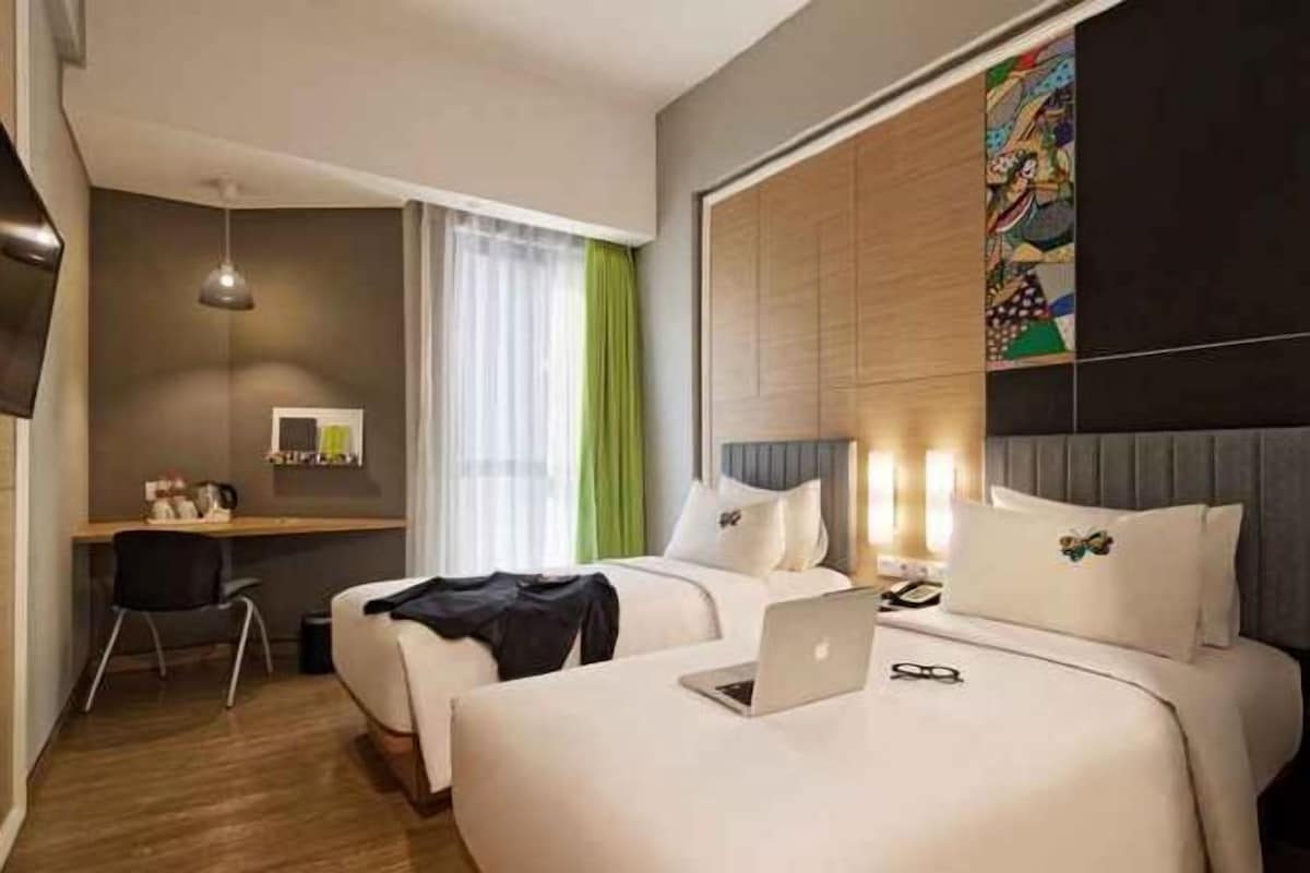 Una habitación de hotel con dos camas, un escritorio, una silla y un televisor.
