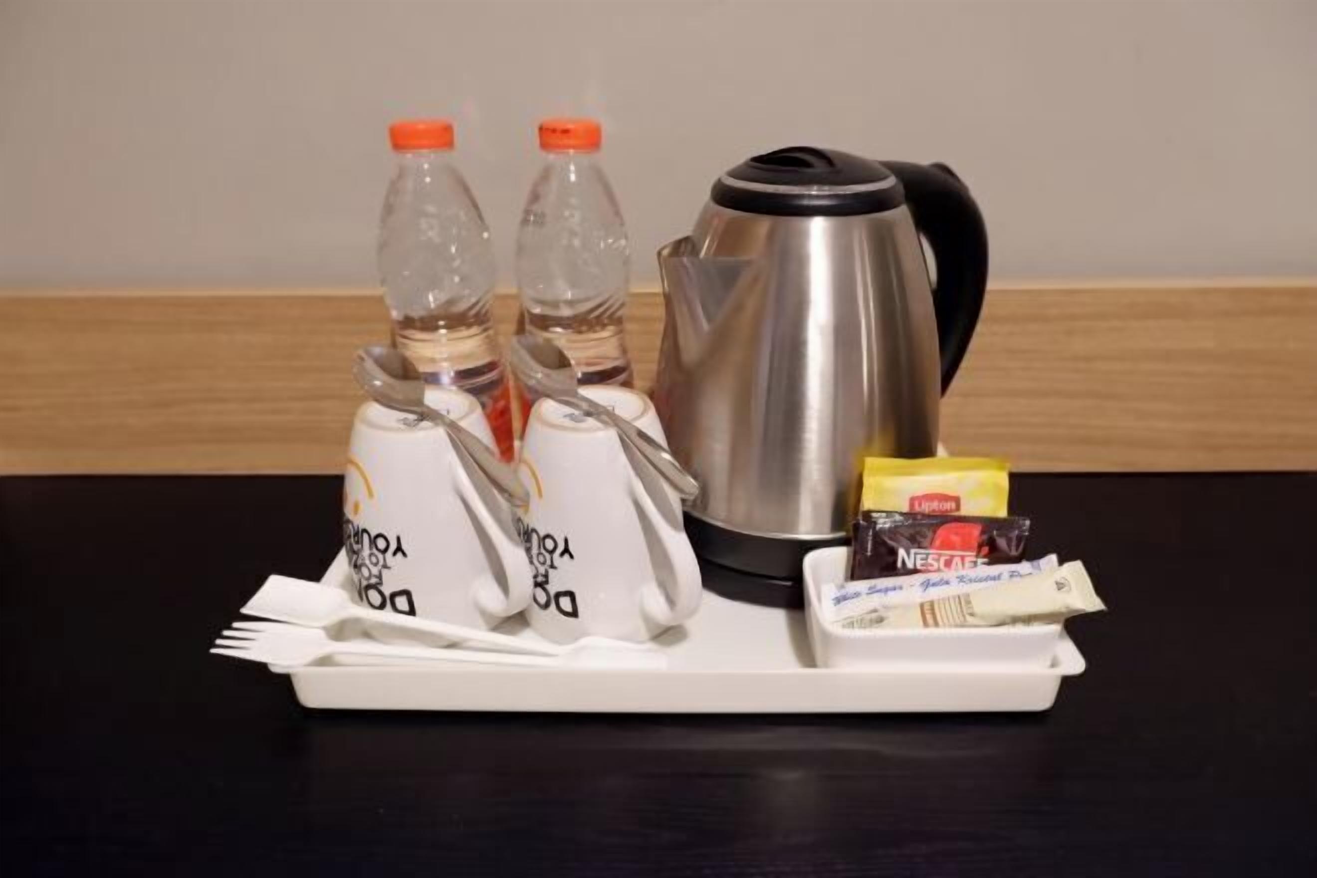 Ein Tablett mit einer Kaffeekanne, zwei Flaschen, einer Packung Lipton Tee, einer Packung Nescafe und einer weißen Tasse mit Aufdruck.
