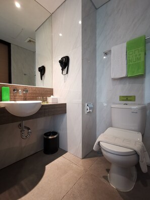 A modern bathroom with a white sink, a toilet, and a mirror. - MaxOneHotels.com at Platinum Hayam Wuruk Jakarta (Jakarta)