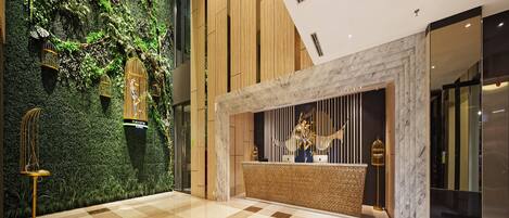 A modern lobby with a green wall, a checkered floor, and a reception desk with a decorative sculpture.