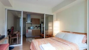 A bedroom with a bed, a desk, and a sliding door leading to a kitchen. - Santorini 1 Bedroom Condo at Azure Urban Residences (Parañaque)