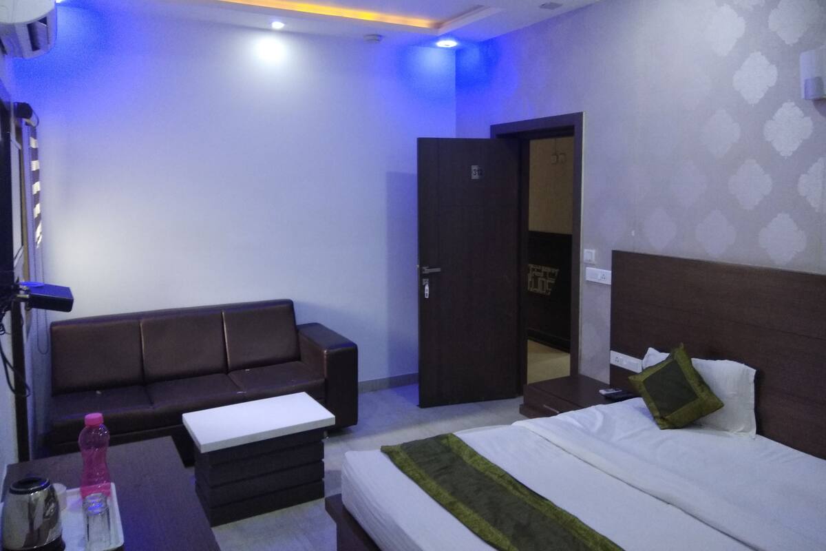 A modern hotel room with a bed, a sofa, a desk, and a wardrobe.