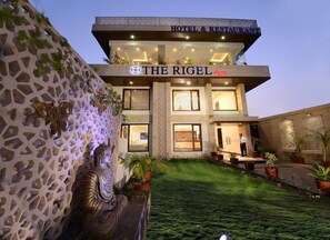 A hotel named 'The Rigel' with a modern architectural design, featuring a prominent Buddha statue in the courtyard.