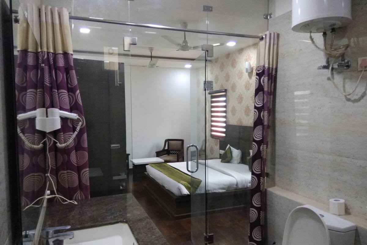 A modern bathroom with a glass shower enclosure, a separate toilet, and a large mirror.