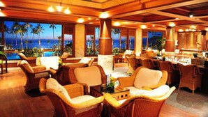 Amplia sala de estar con muebles de mimbre, un bar y vistas al océano.