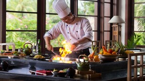 Un chef cocina con una parrilla en una habitación con ventanas amplias y vistas a zonas verdes.