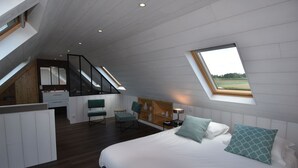 Slaapkamer met een groot bed, een bureau en een stoel, een dakraam en uitzicht op de omgeving.