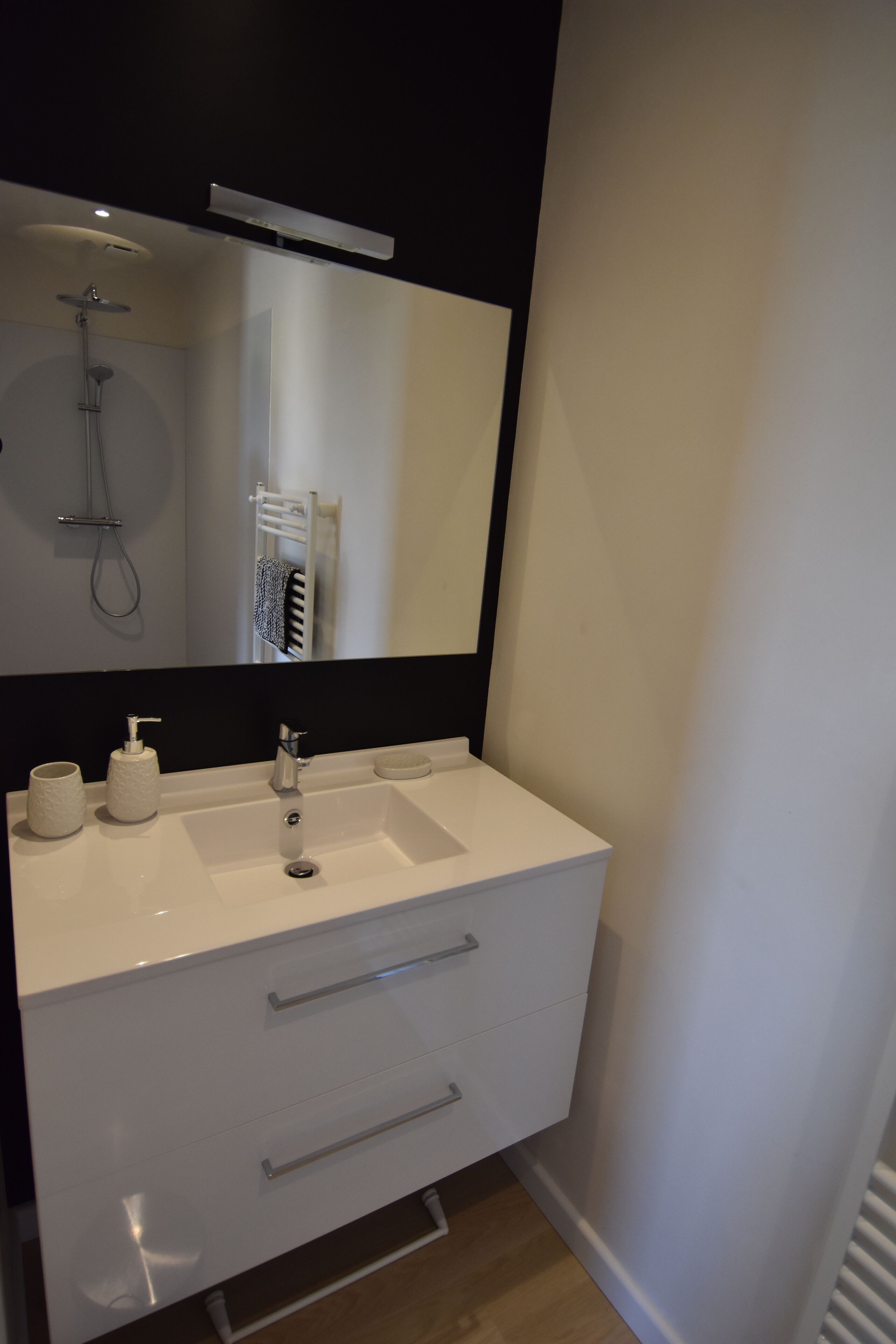A modern bathroom with a white sink, a mirror, and a towel rack.
