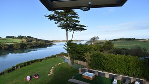 Uitzicht op een rivier vanaf een balkon met een hottub, lounge fauteuils en een gazon.