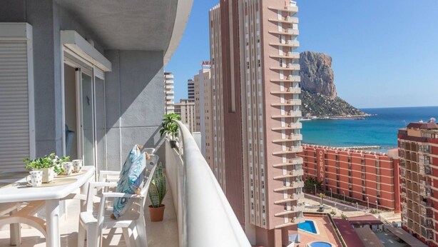 A balcony with a view of a coastal cityscape, including a prominent building with the name 'OCEAN' and a rocky outcrop in the distance. - Apartamento Apolo XIV  by Costa CarpeDiem (Calp)