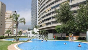 A swimming pool surrounded by greenery and tall buildings. - Apartamento Apolo XIV  by Costa CarpeDiem (Calp)