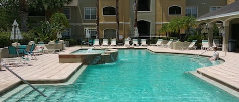 A swimming pool with lounge chairs and a building in the background.