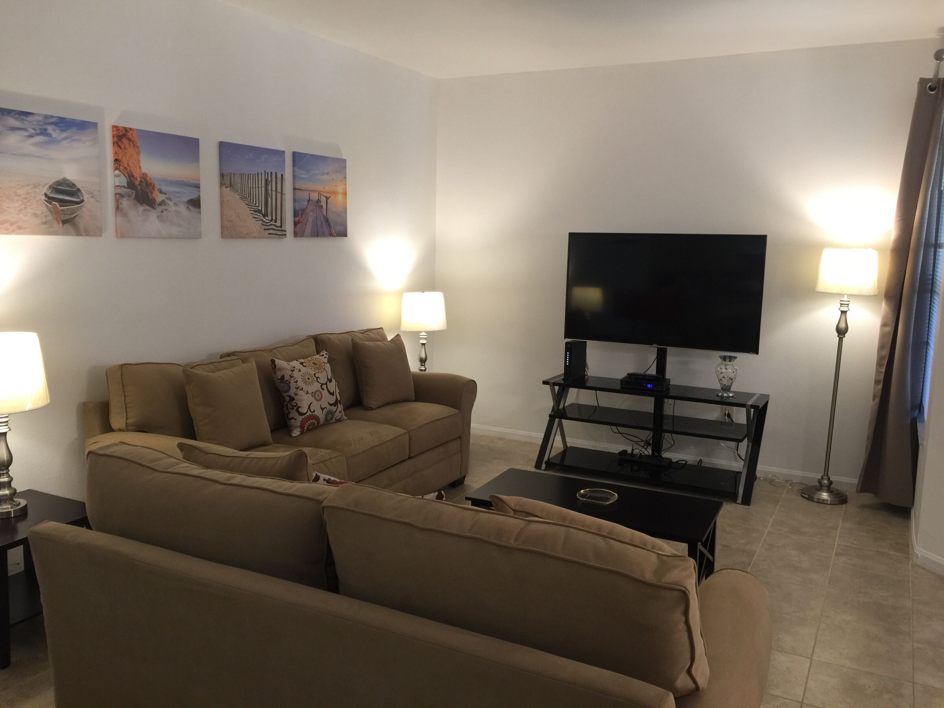 A living room with a sofa, a TV on a stand, and two lamps.