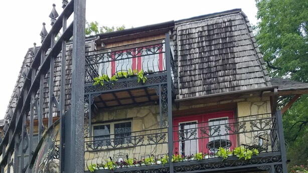 Un immeuble de deux étages doté de balcons, de murs en pierre et de volets rouges.