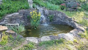 Un jardin avec un petit étang, un mur de pierre et une statue.