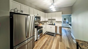 Una cocina moderna con electrodomésticos de acero inoxidable, armarios blancos y suelo de madera.