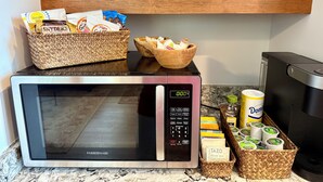 Une cuisine équipée d’un four à micro-ondes Farberware, d’un grille-pain, ainsi que de divers aliments et récipients disposés sur le plan de travail.
