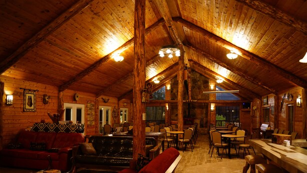 L’intérieur chaleureux d’un chalet en bois comprend un coin repas, des sièges et une cheminée.