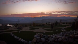 Un espace paysager agrémenté d’un mur de pierre et offrant une vue sur des montagnes lointaines au coucher du soleil.