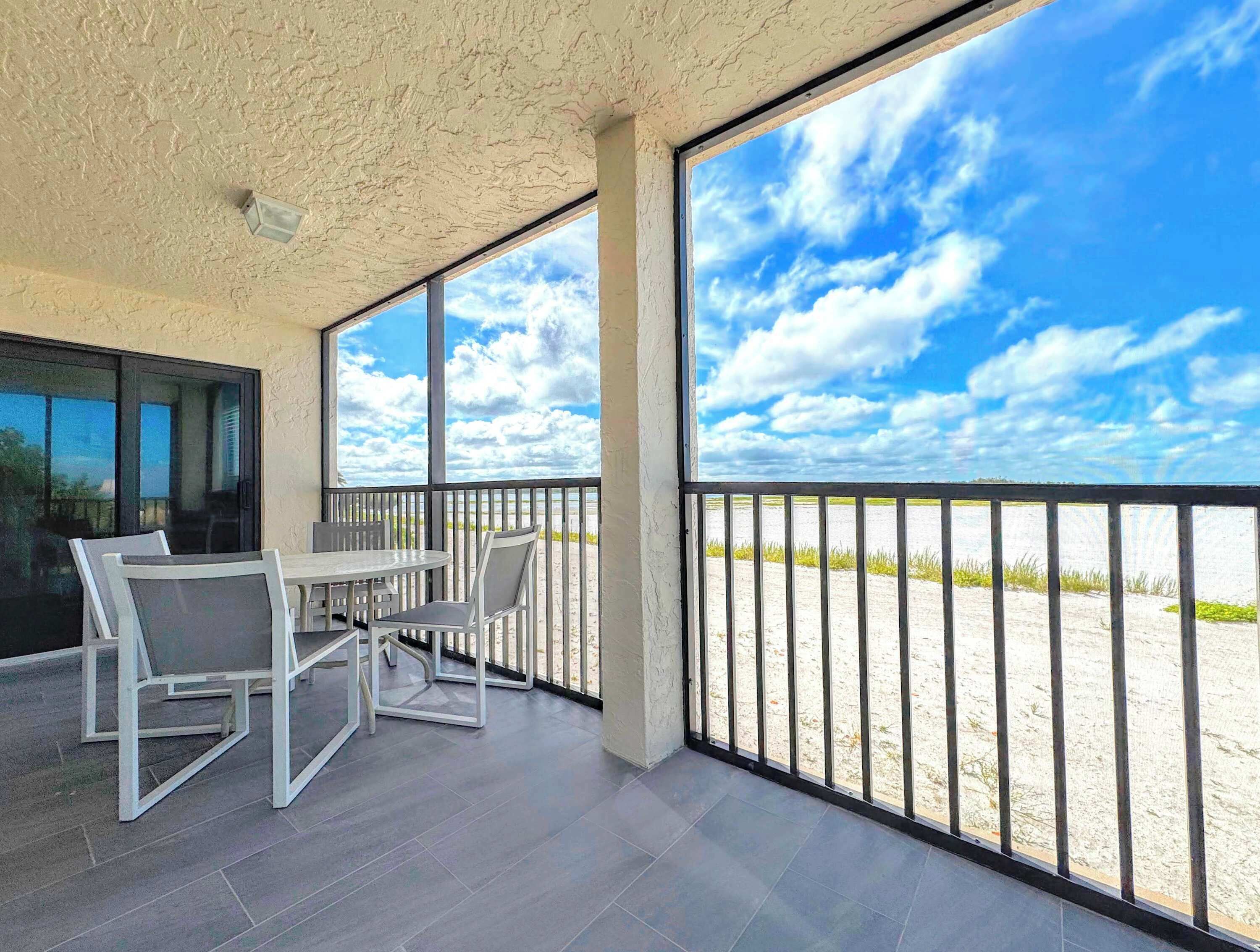 A covered outdoor seating area with a view of the beach and sky.