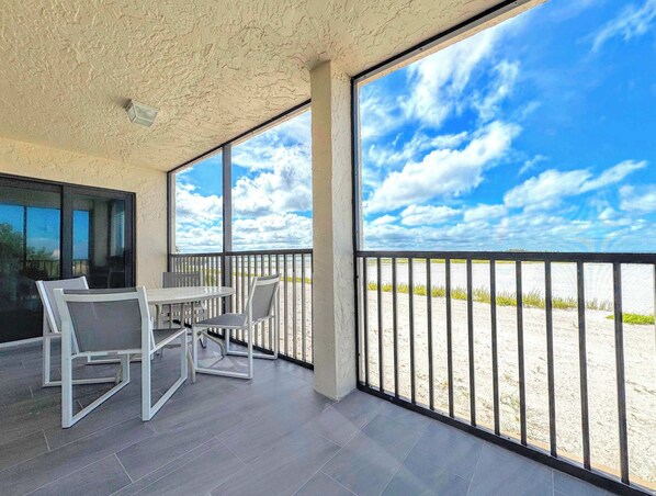 A covered outdoor seating area with a view of the beach and sky.