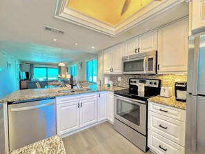 A modern kitchen with white cabinetry, stainless steel appliances, and a granite countertop. - Carlos Pointe #136 Tropical Beachfront Condo (Fort Myers Beach)